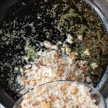 Bread crumbs being tipped into pan with a some oil in the bottom.