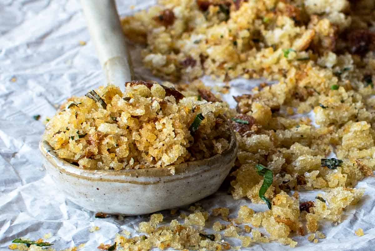 A close up of golden brown bread crumbs in a stone ware spoon.