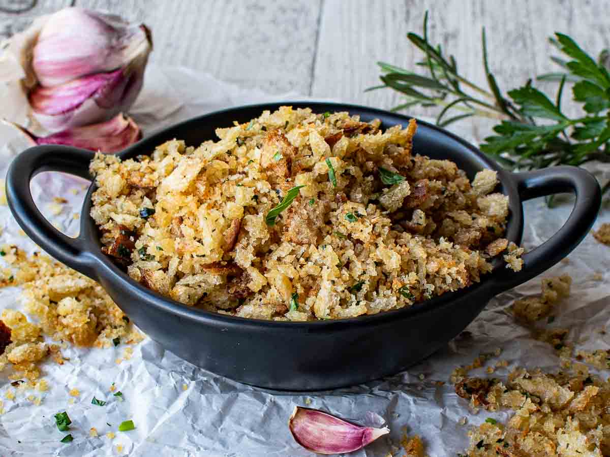 A black bowl filled with golden brown bread crumbs with some spilling over.