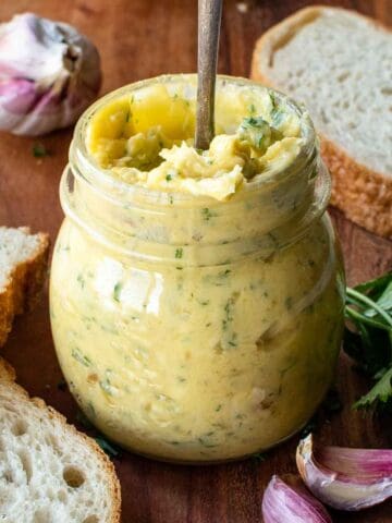 Roasted garlic butter in a jar with a spoon inserted.