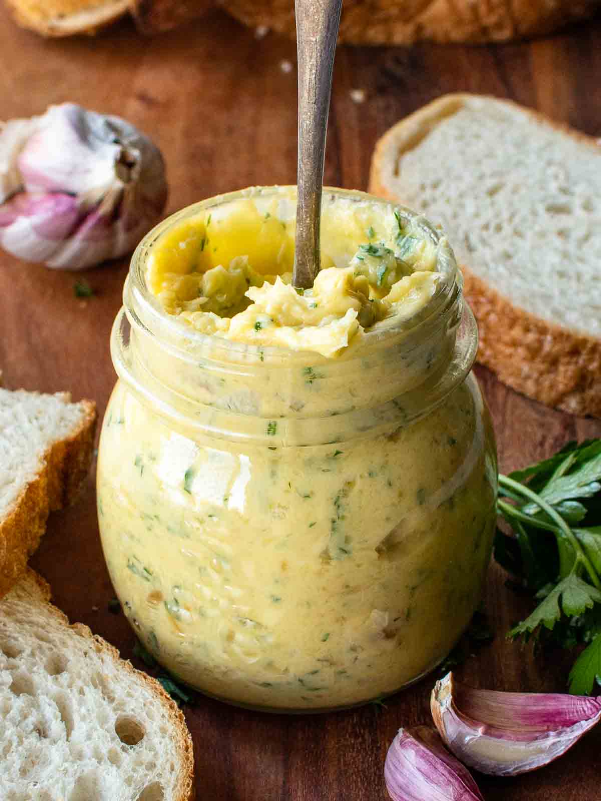 Roasted garlic butter in a jar with a spoon inserted.