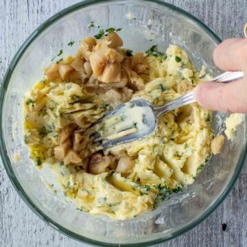 Butter, garlic and parsley mixture begin mixed with a fork.