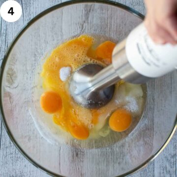 Eggs and sugar being whisked with an emersion blender. 