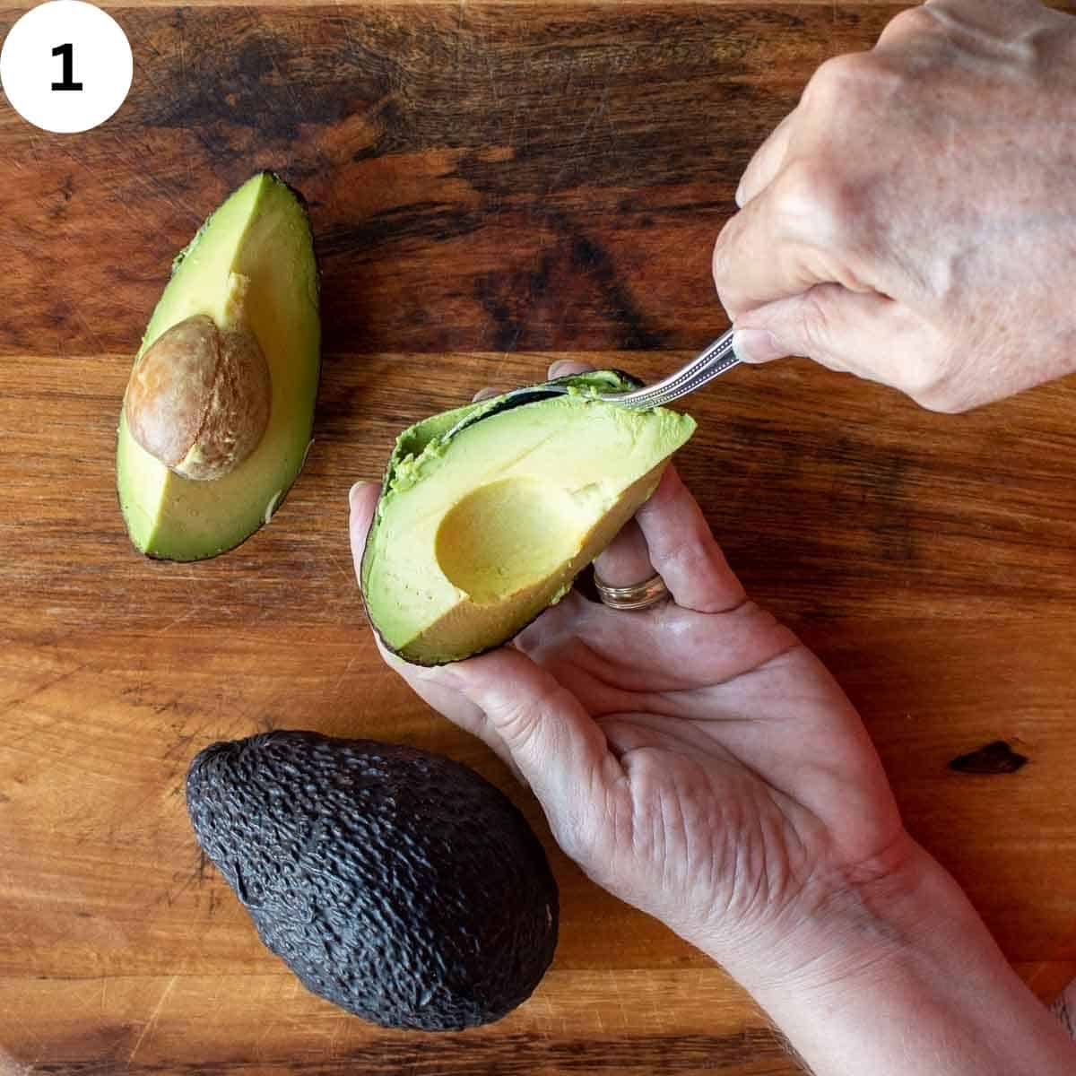 Avocado cut into quarters and being peeled.