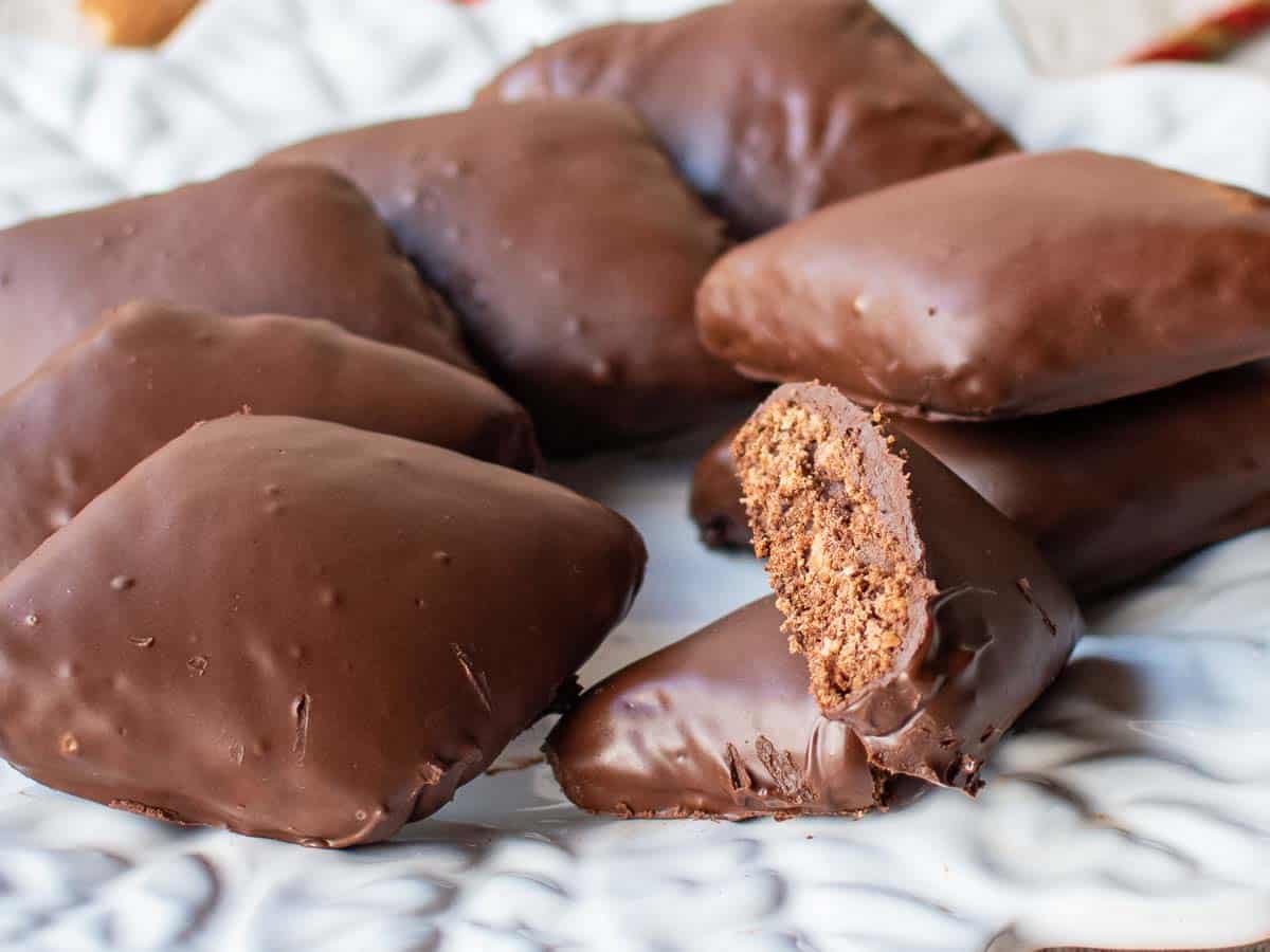 Chocolate coated, diamond shaped cookies on a plate with one cut in half.