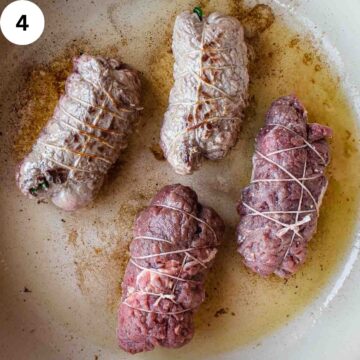 Rolled beef steaks being browned in a pan.