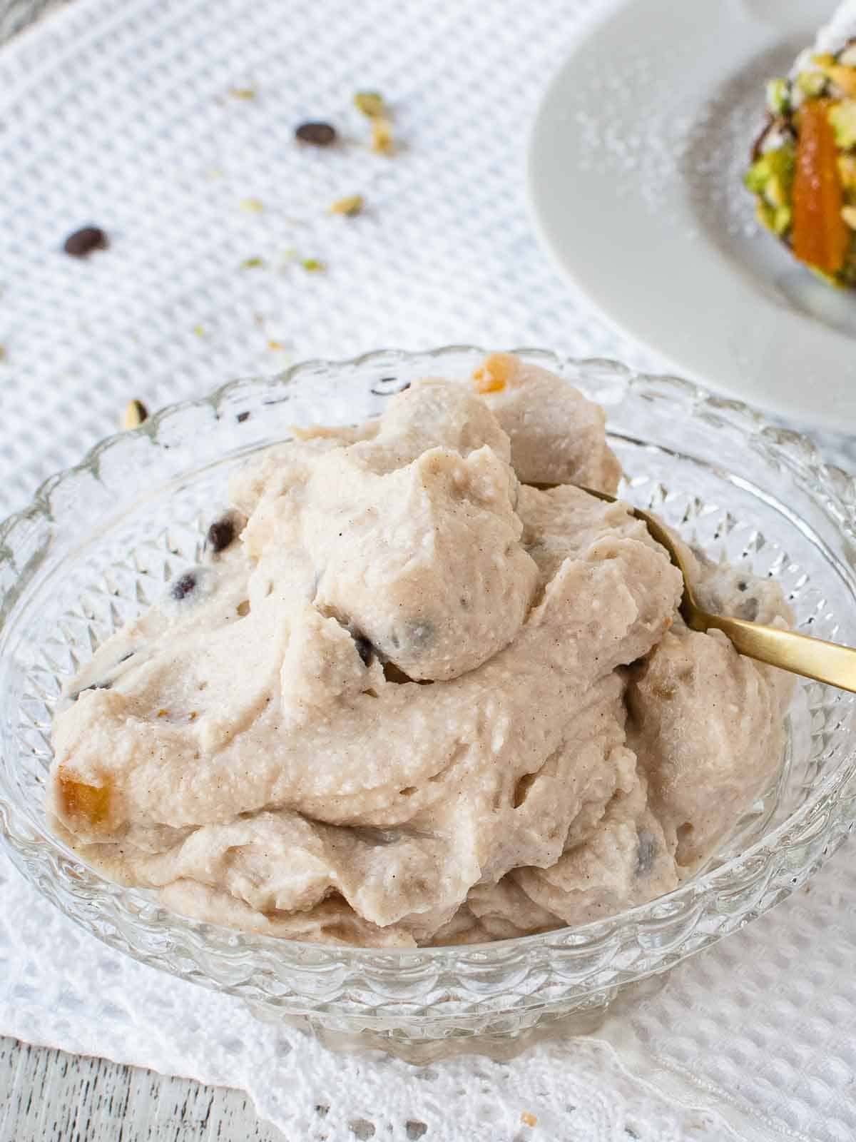 Cannoli filling in a glass bowl with gold spoon.