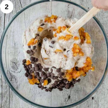 Chocolate and chopped candied orange being stirred into a creamy mixture.