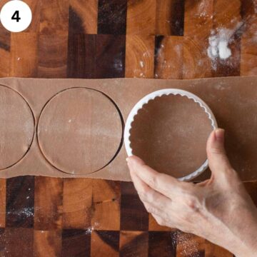 Circles being stamped out of thin, brown pasta dough.