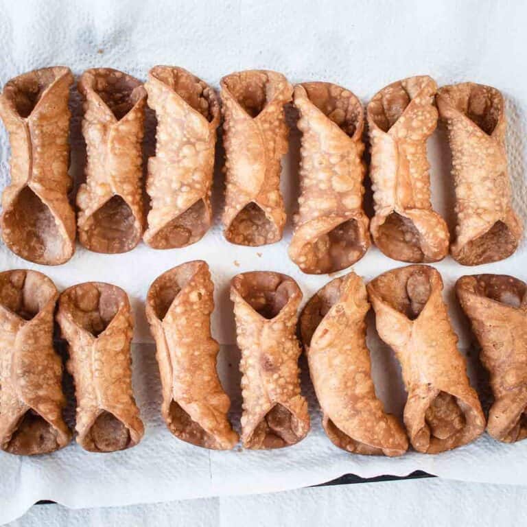 Overhead view of fried shells for cannoli lined up on paper towel.