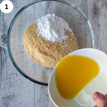 Cookie crumbs and sugar in a bowl with melted butter being added.