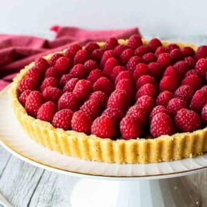 Chocolate Raspberry Tart on a white footed cake plate.