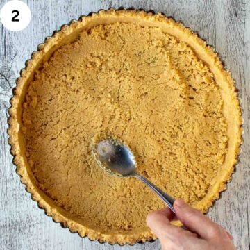 Cookie crumb crust being pressed into a tart pan.