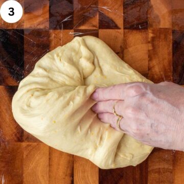 Soft dough being folded and kneaded by hand.