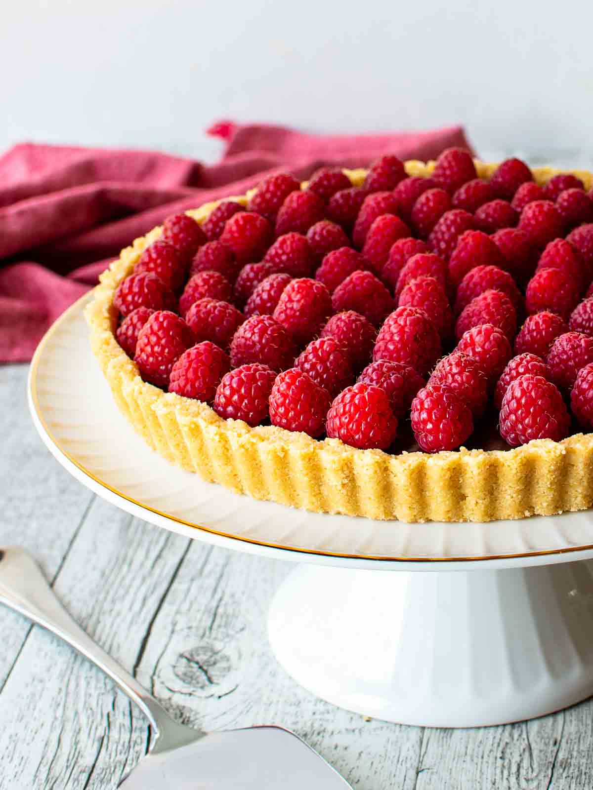 Chocolate Raspberry Tart on a white footed cake plate.
