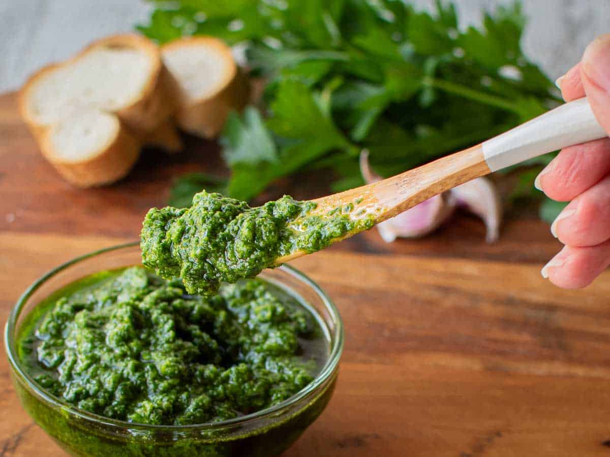 Thick herb sauce in a bowl with a spoonful being lifted out