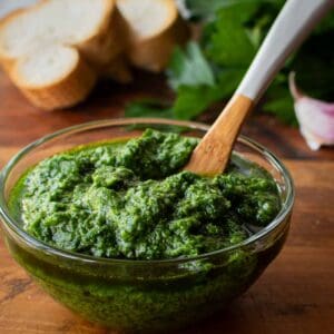 Italian salsa verde in a glass bowl with a painted wooden spoon in it.