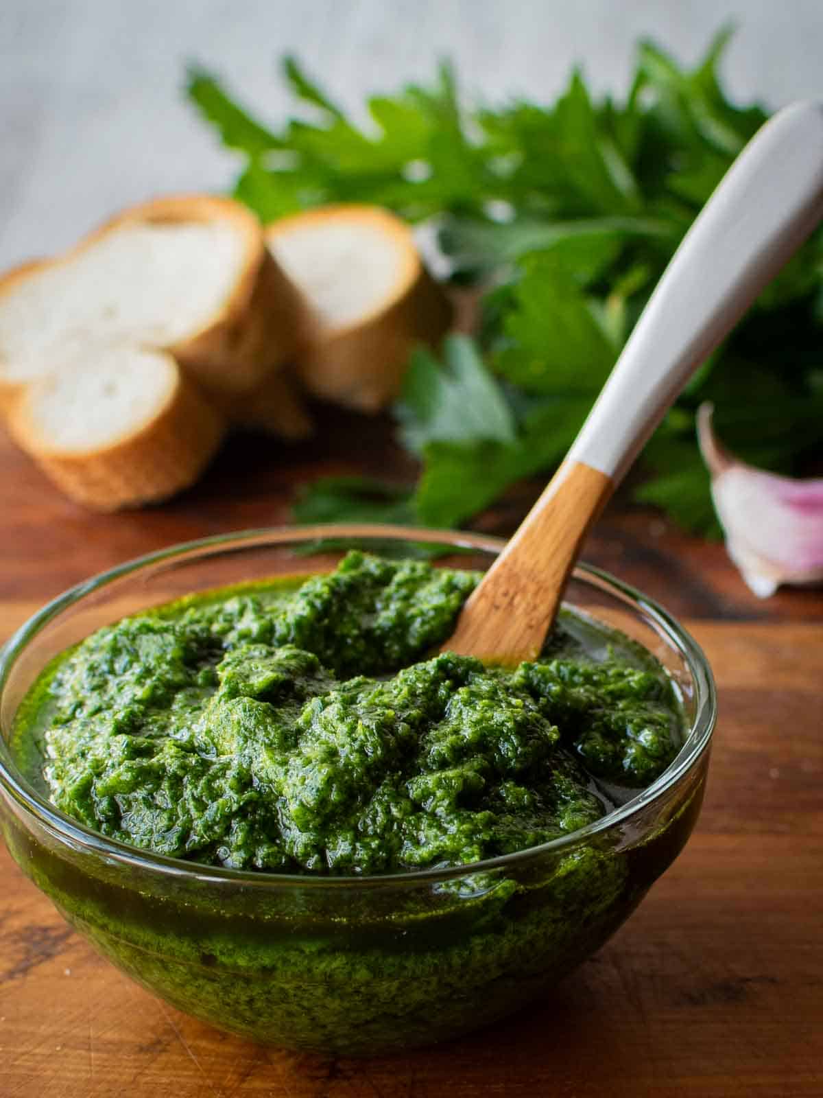 Italian salsa verde in a glass bowl with a painted wooden spoon in it.