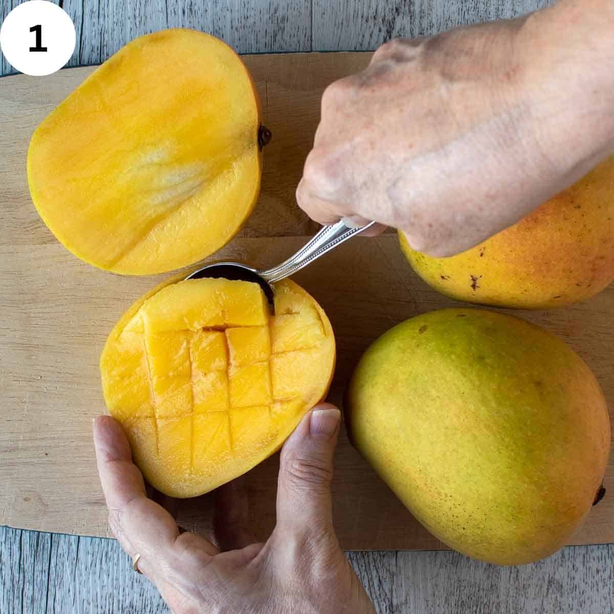 Scooping the flesh from a mango half.