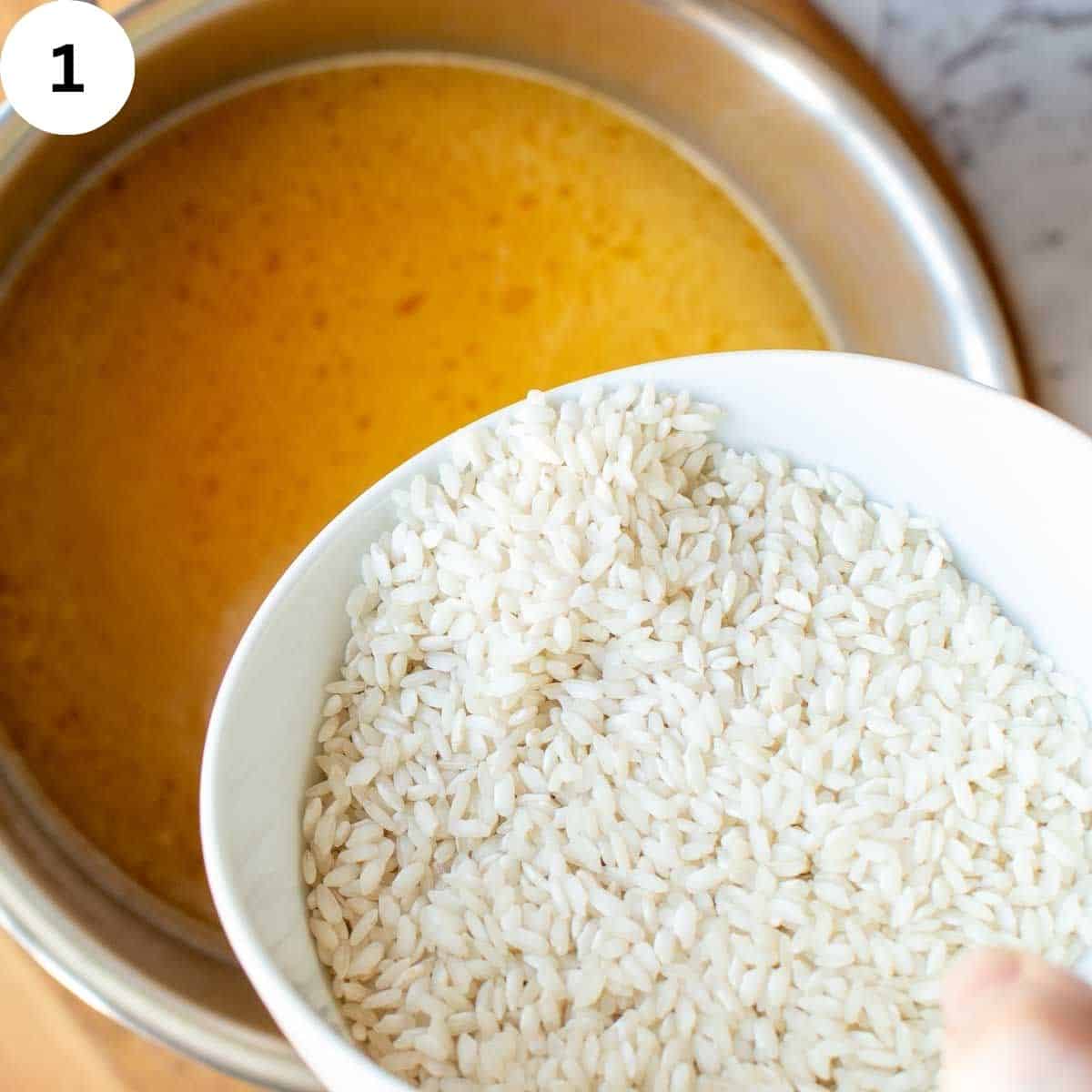 Raw rice being poured into broth.