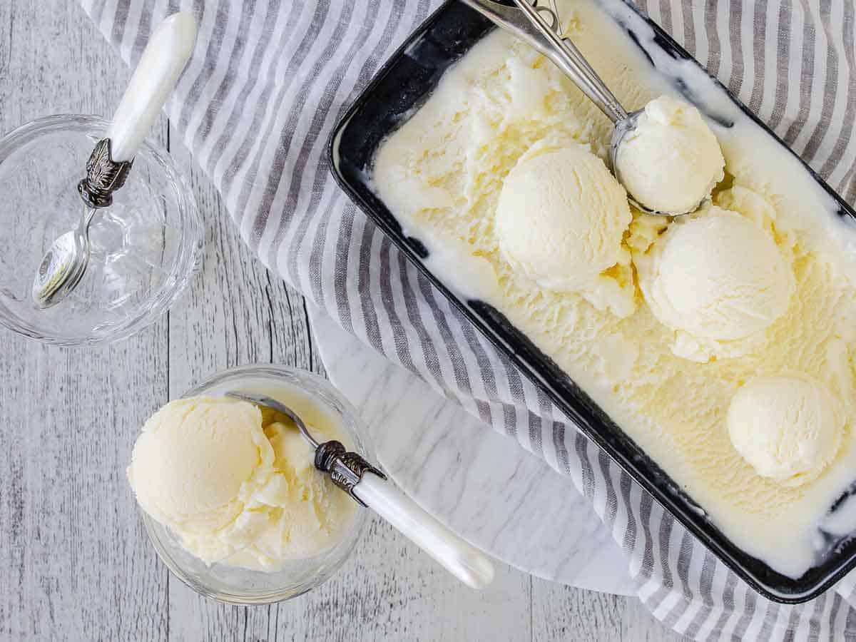 Overhead view of ice cream in a loaf pan with some balls scooped and scoops in a glass dessert bowl. #FrozenDessert #SicilianIceCream #ItalianGelato