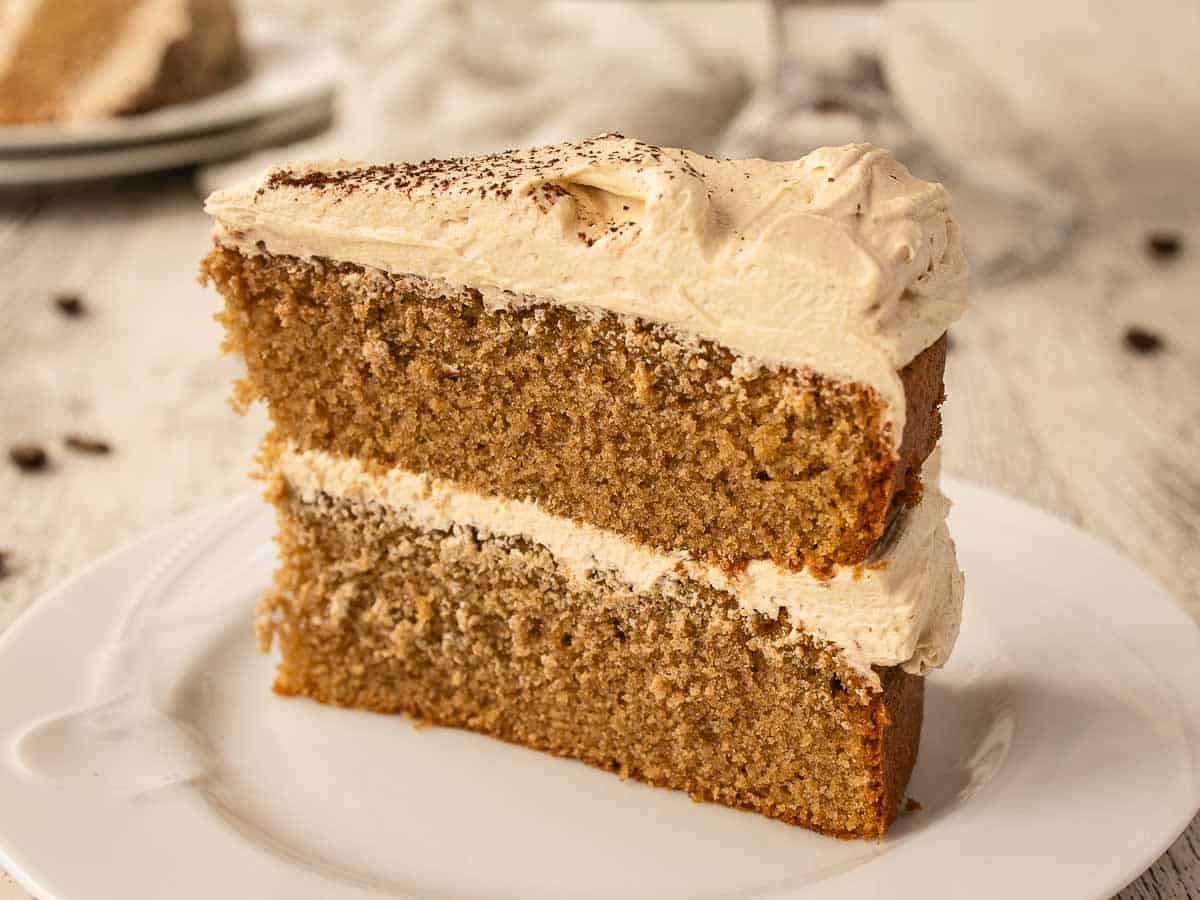 Close up of a wedge of two layer cake filled and topped with buttercream.
