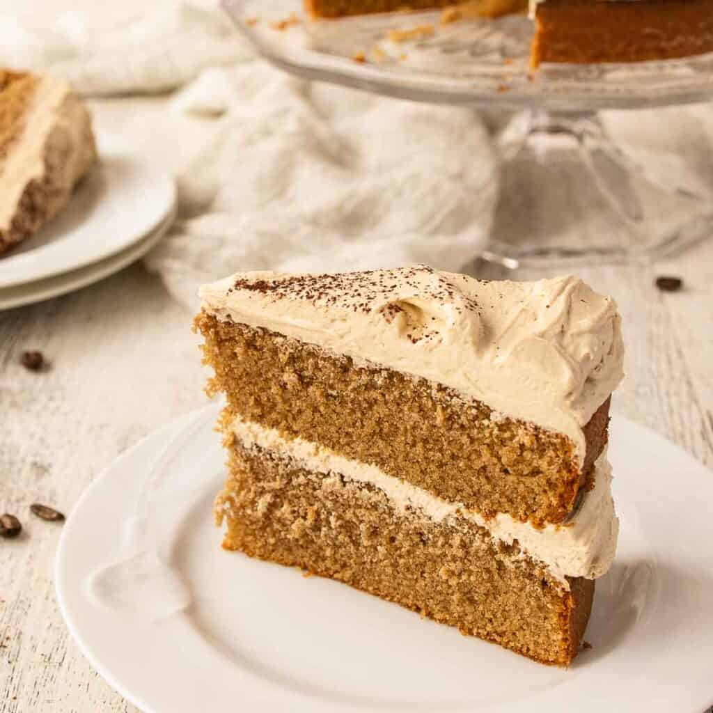 Cappuccino Cake with a slice on a plate and remaining cake in background.