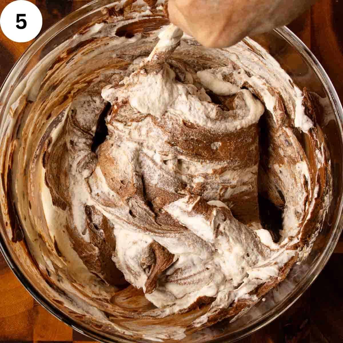 White and chocolate mixtures being folded together in a bowl.