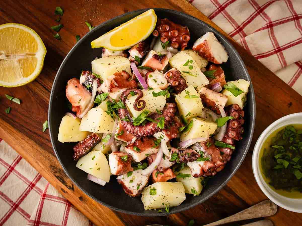 Overhead view of a bowl of salad made up of pieces of octopus tentacles and potatoes.