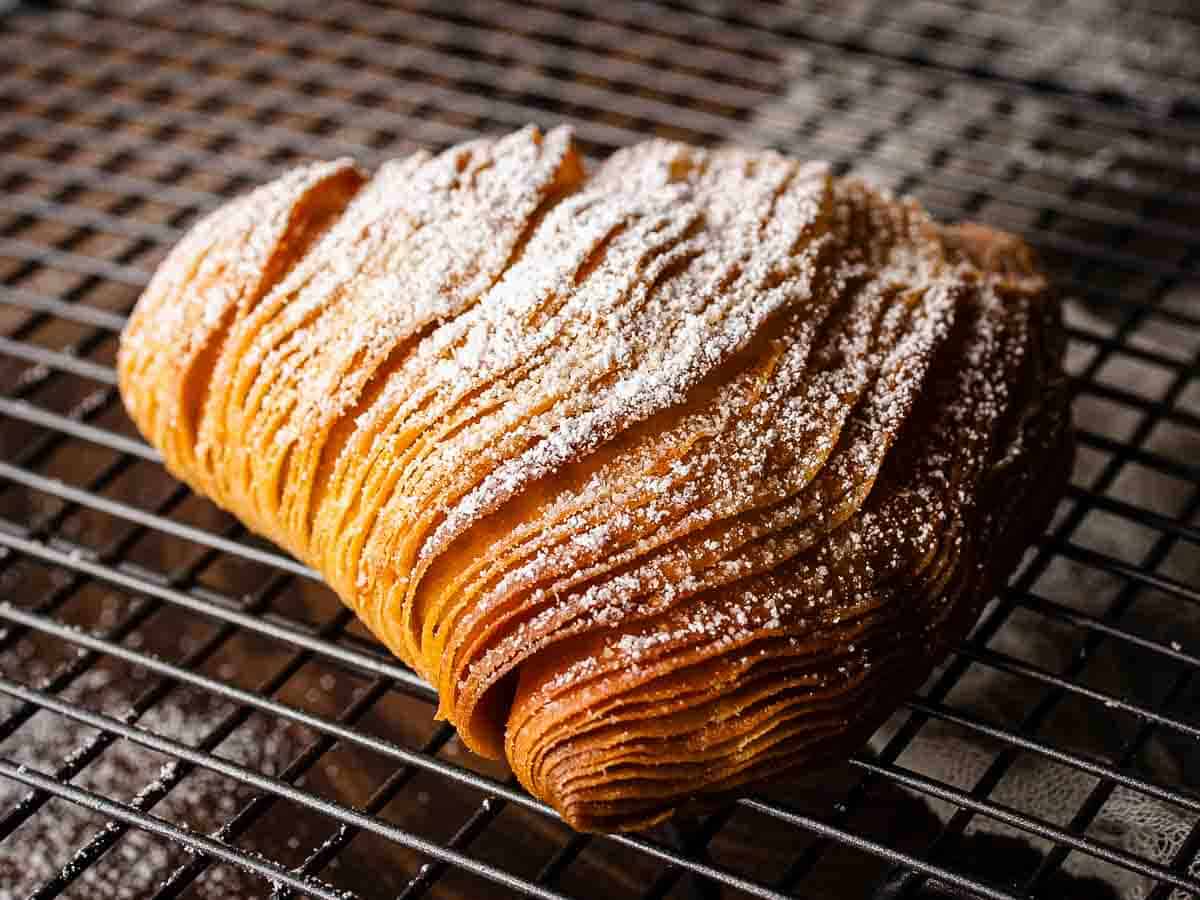 A close up of this flaky pastry with many pastry layers dusted with powdered sugar.