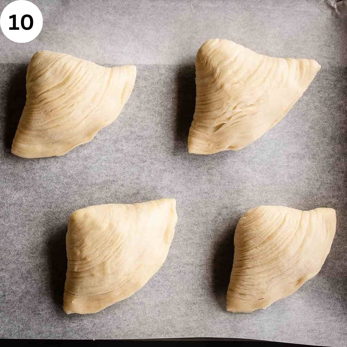 Clam shaped pastries arranged on a parchment lined baking sheet.