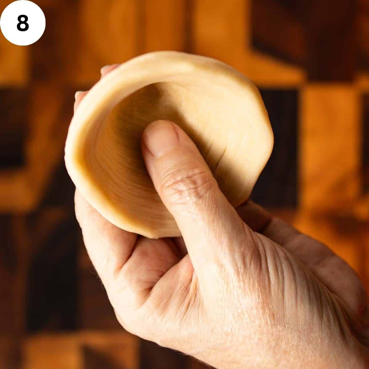 Pastry being shaped into a short cone shape.