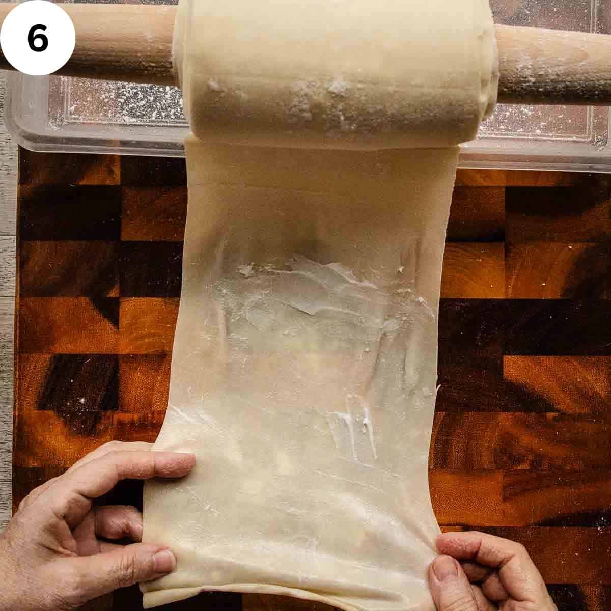 A length of thinned dough being smeared with fat.
