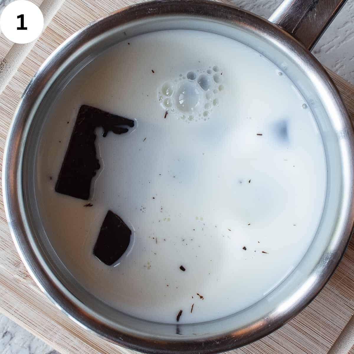 Blocks of chocolate partly floating in a saucepan of milk.