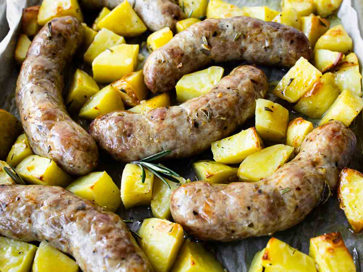 Close up of sausages baked with potatoes.