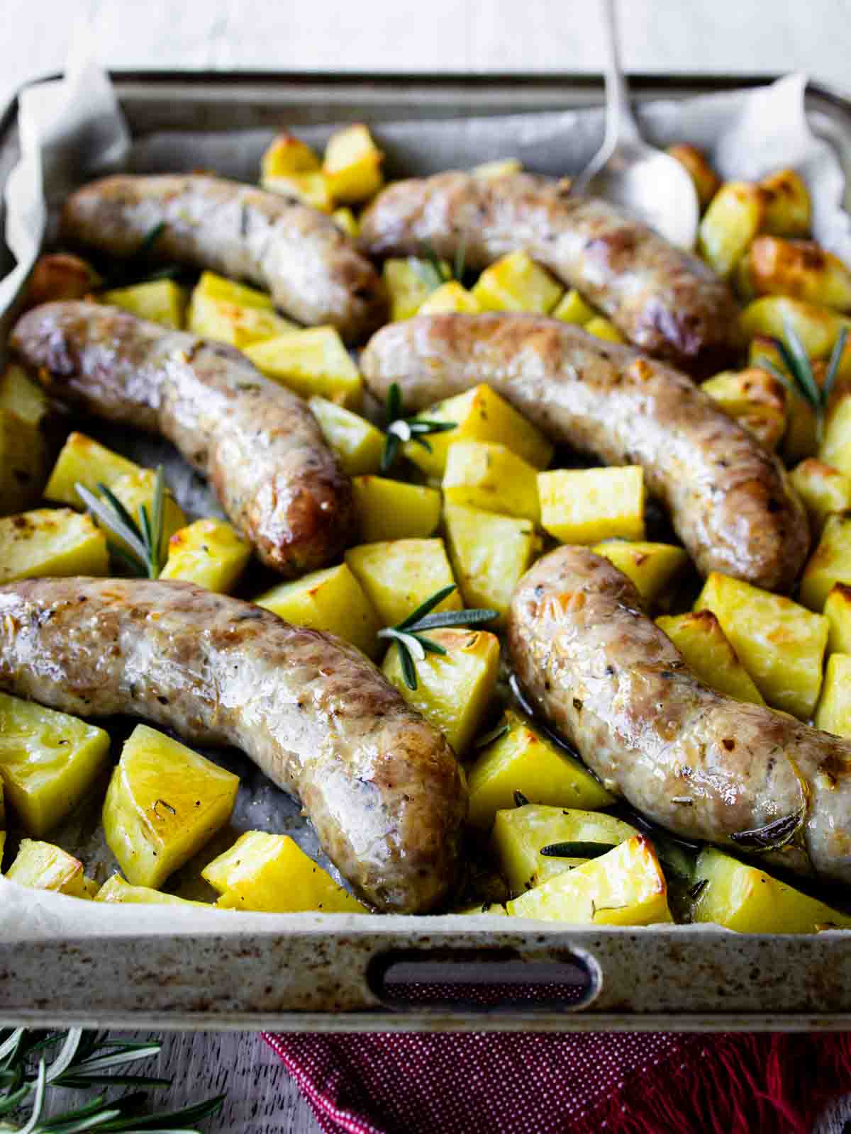 Baked Italian sausage and potatoes in a baking dish.