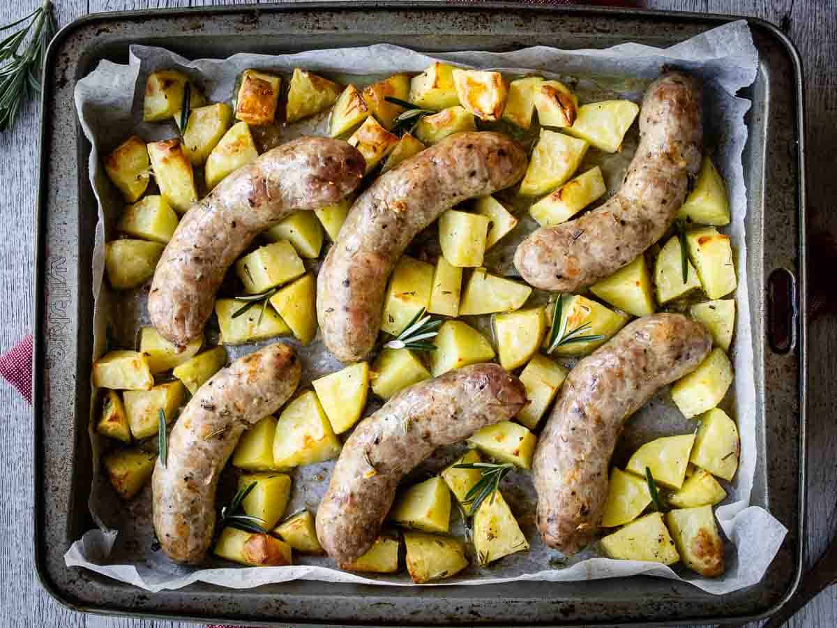 Overhead view of baked sausages and potatoes.