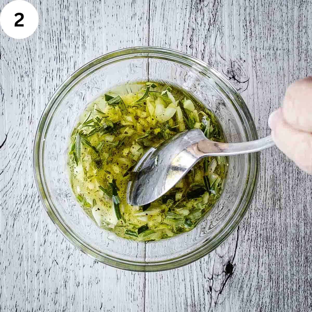 Mixing an oil and herb mixture in a small glass bowl.