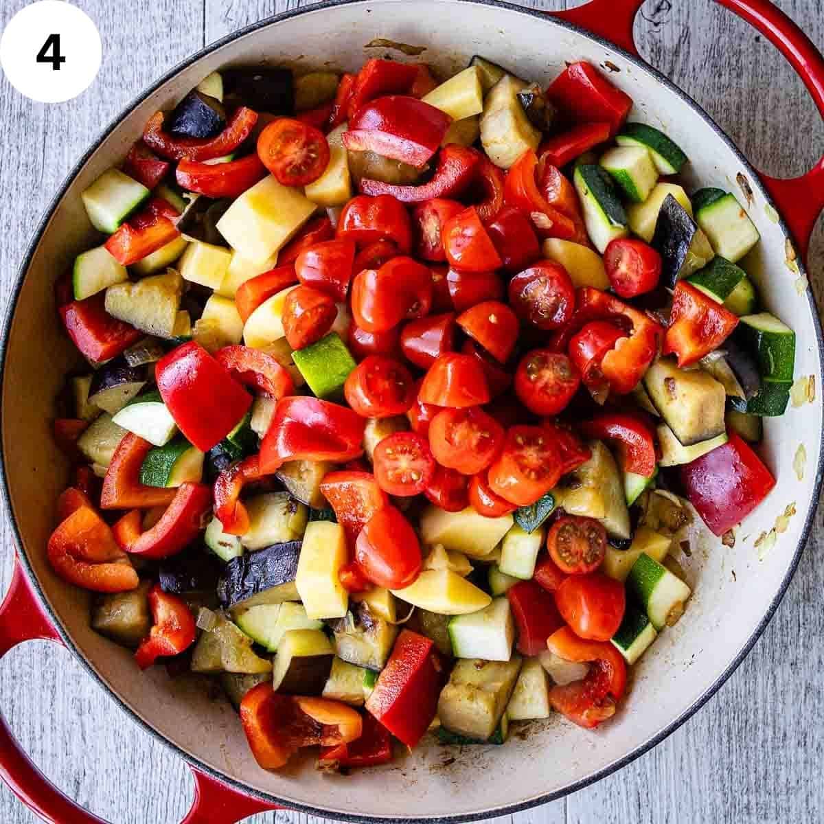Tomatoes added to chopped vegetable in a round pan.