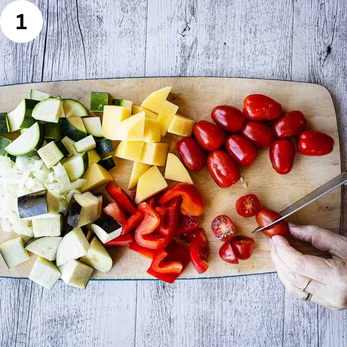 Chopping an array of summer vegetables on a wooden chopping board.