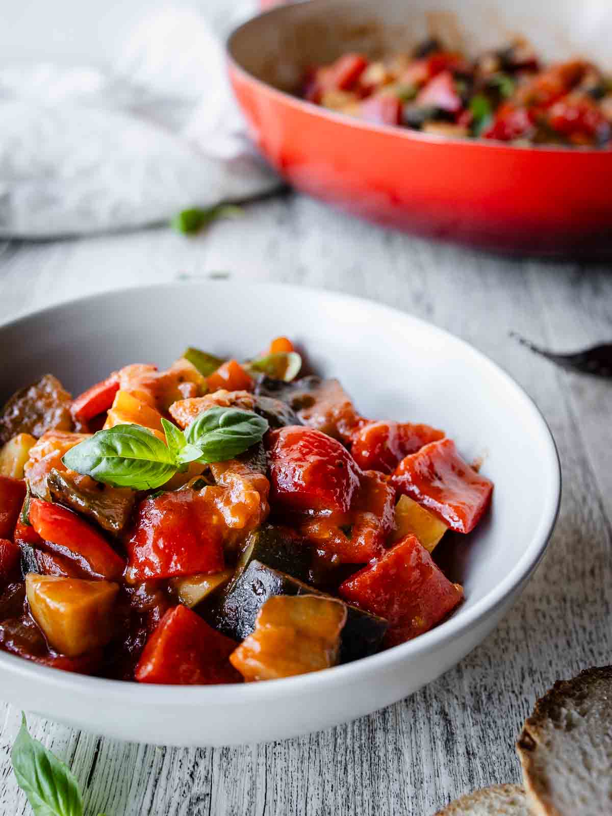 Ciambotta in a bowl with more in the background in a round pan.