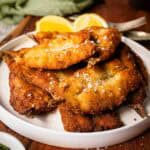 Fried sardines piled up on a round plate.