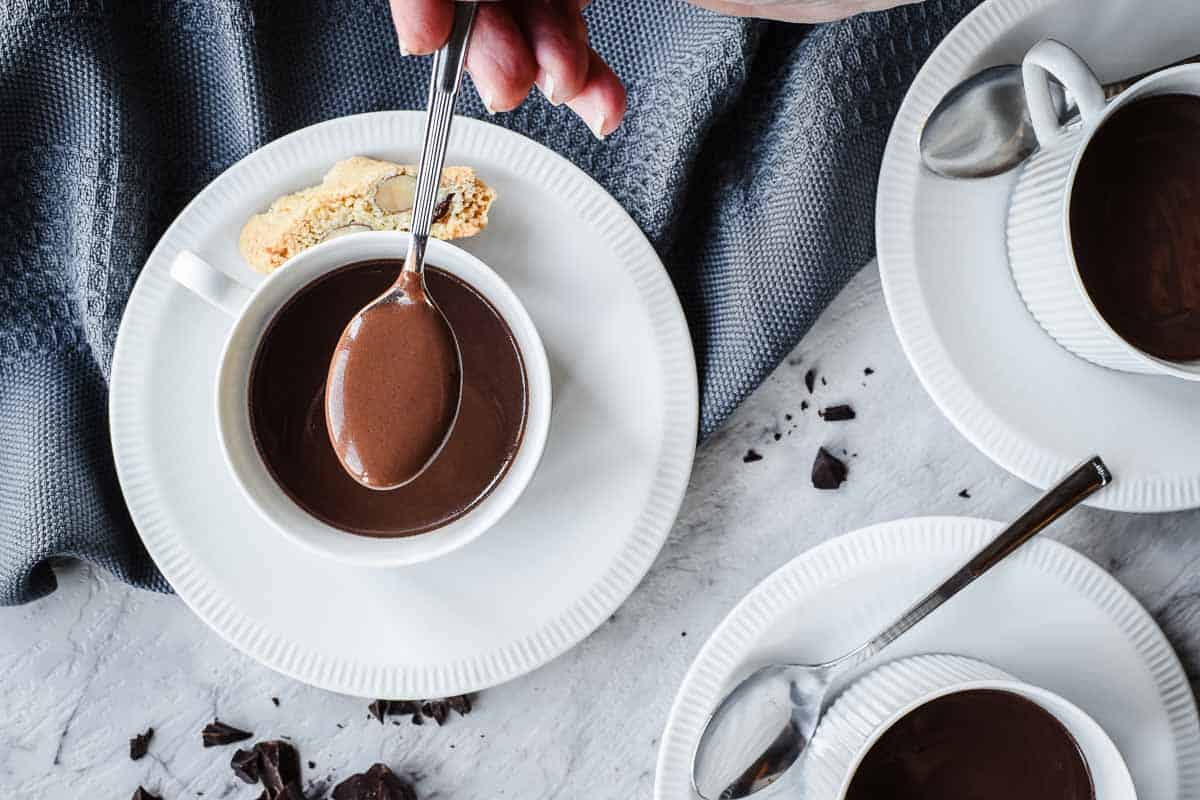 A spoonful of thick chocolate mixture held above a cupful of the mixture.