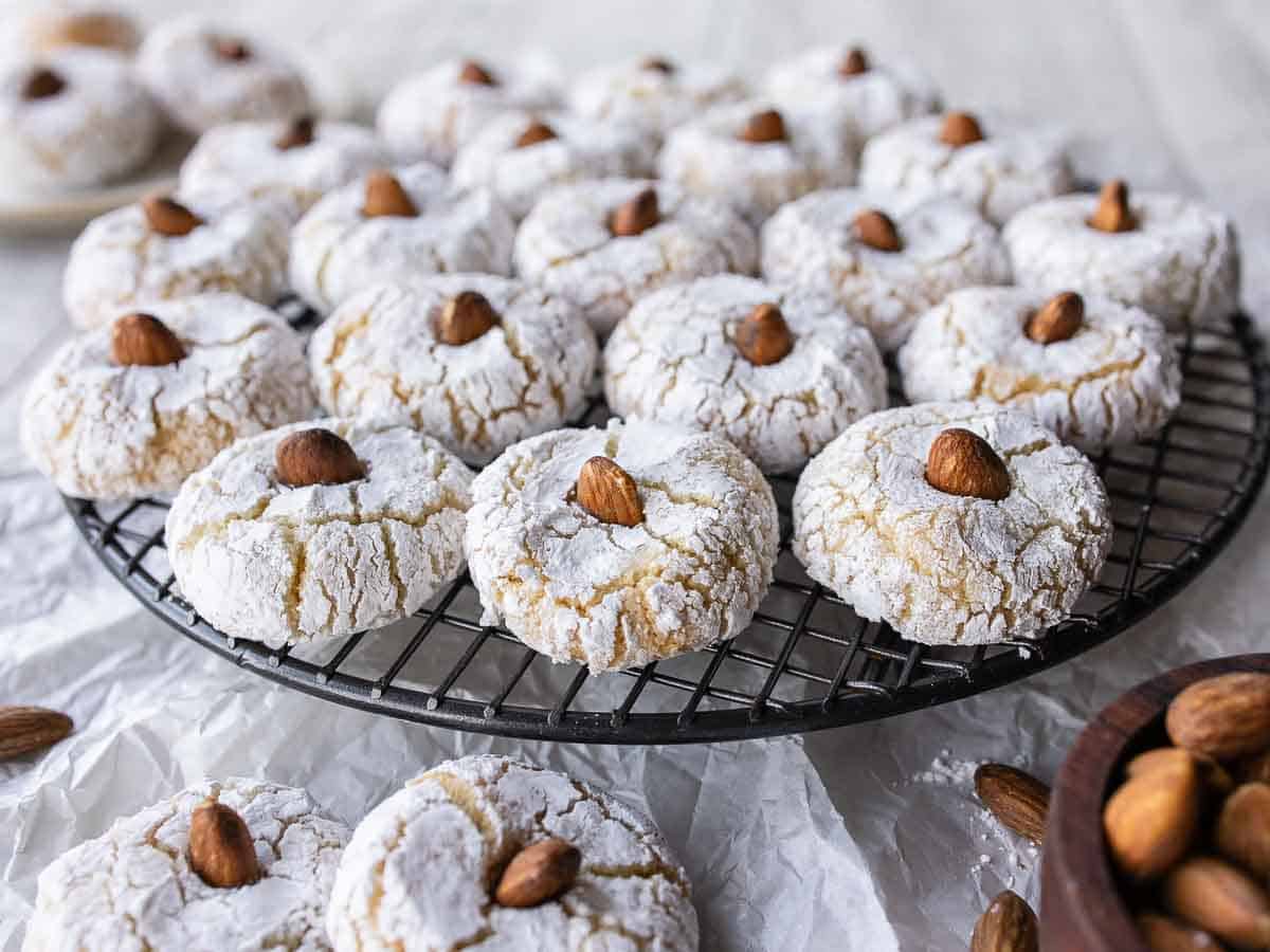 Close up of cookies with almond on top on a round  wire rack.