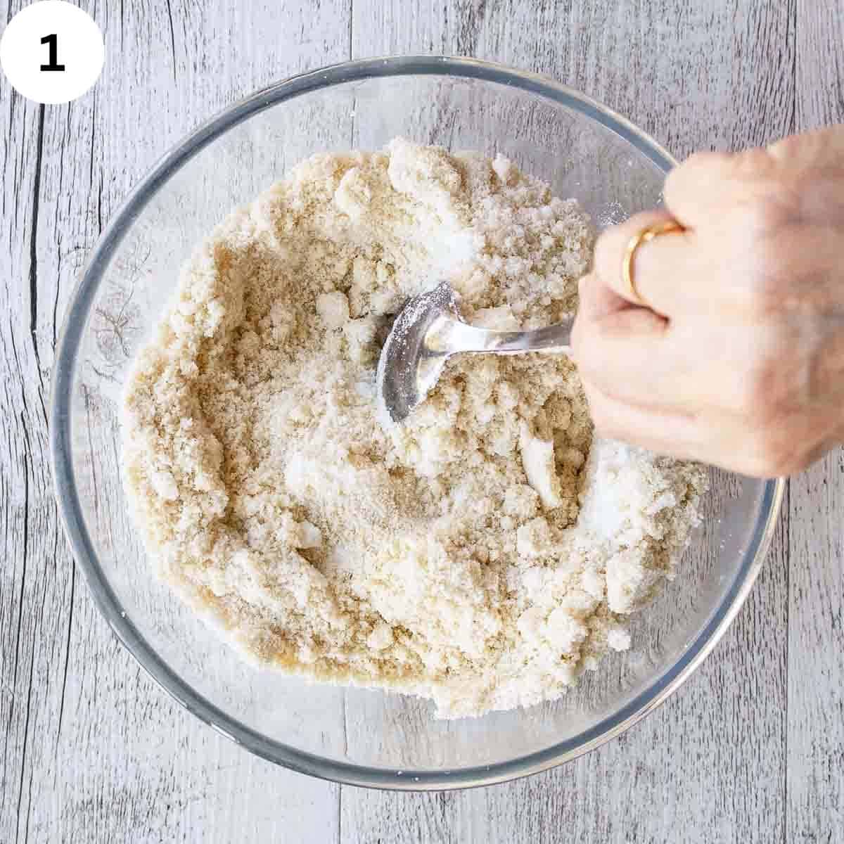 Almond flour and sugar being stirred in a bowl.
