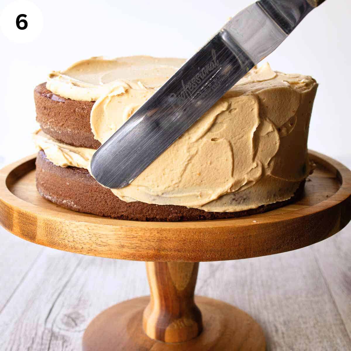 Spreading buttercream on the side of a two layer cake.