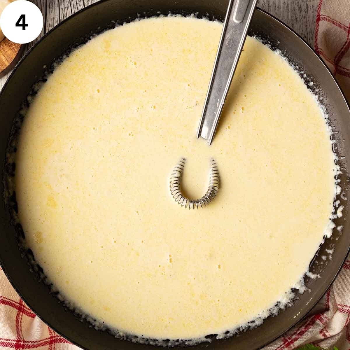 Creamy sauce being whisked in a skillet.