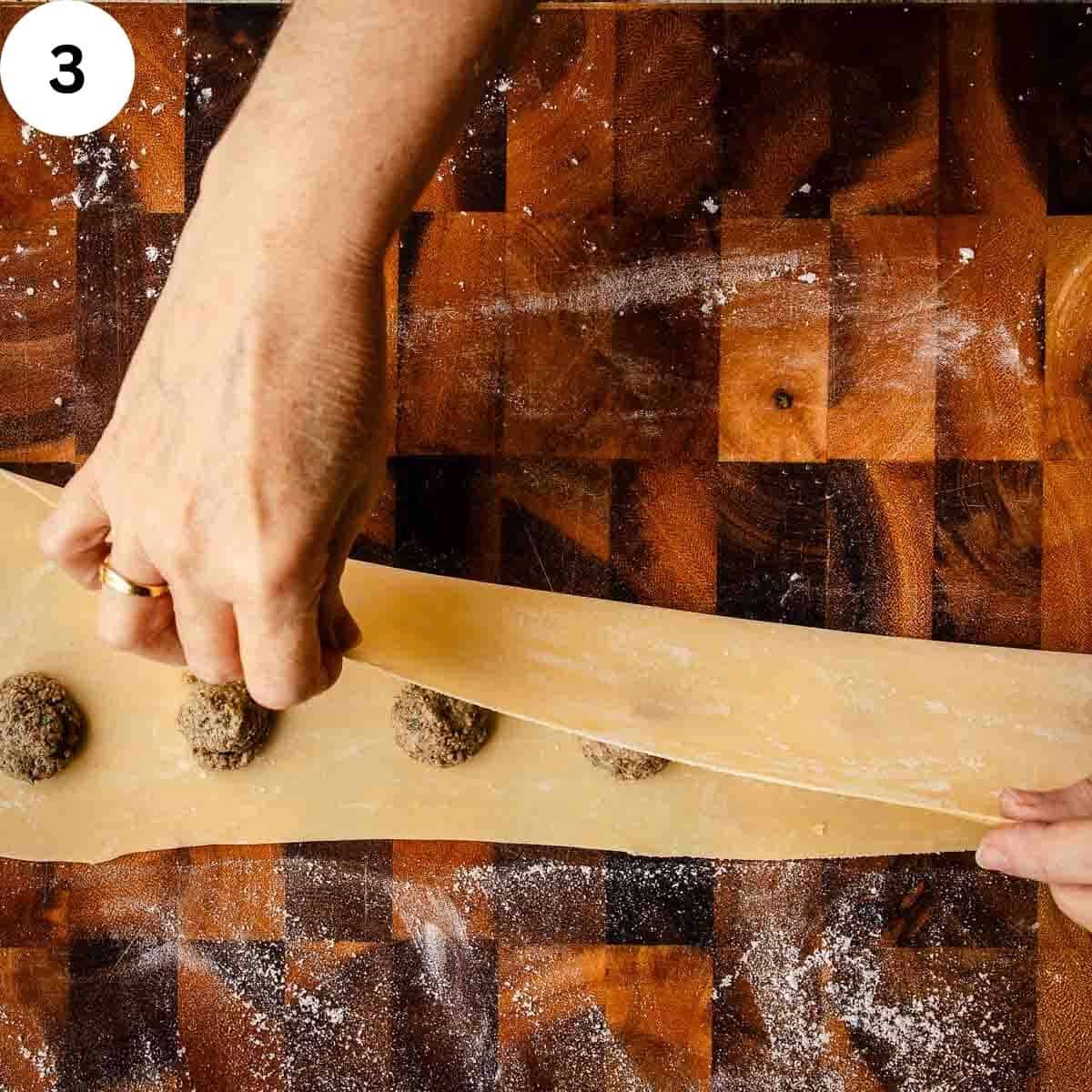 Folding thinned pasta dough over mounds of mushroom filling.