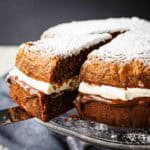 A two layered Nutella Cake filled with gooey chocolate and cream with a slice cut.