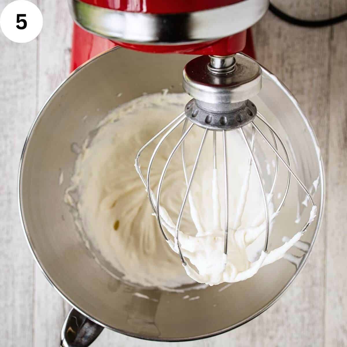 Whipped cream in the bowl of a stand mixer.